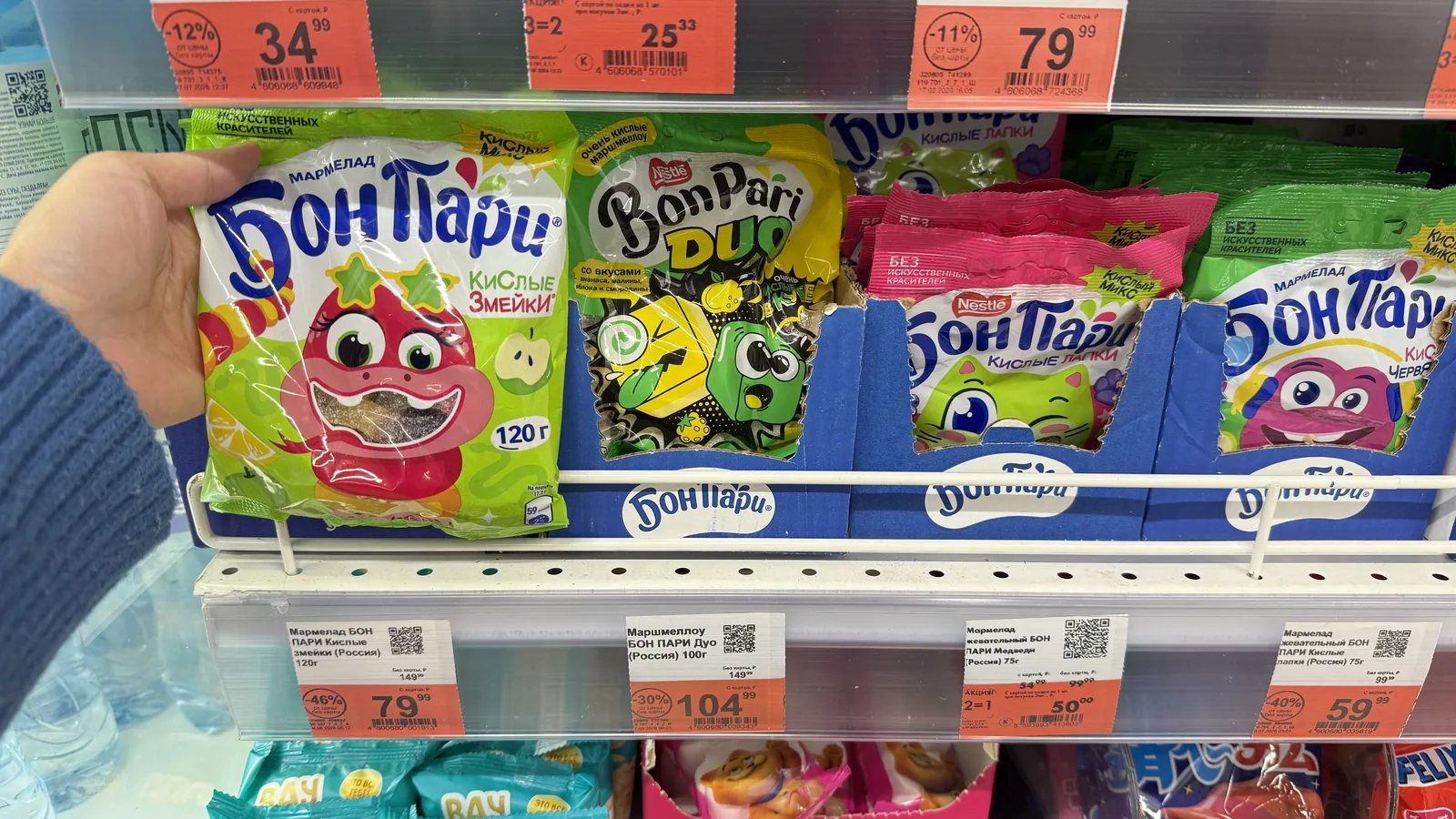 A shopper picking a candy pouch from a convenience shelf — the impulse moment coffee gummies are designed for